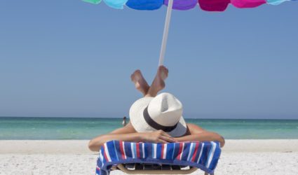 Woman in sunhat lounging on Anna Maria Island beach in beach chair